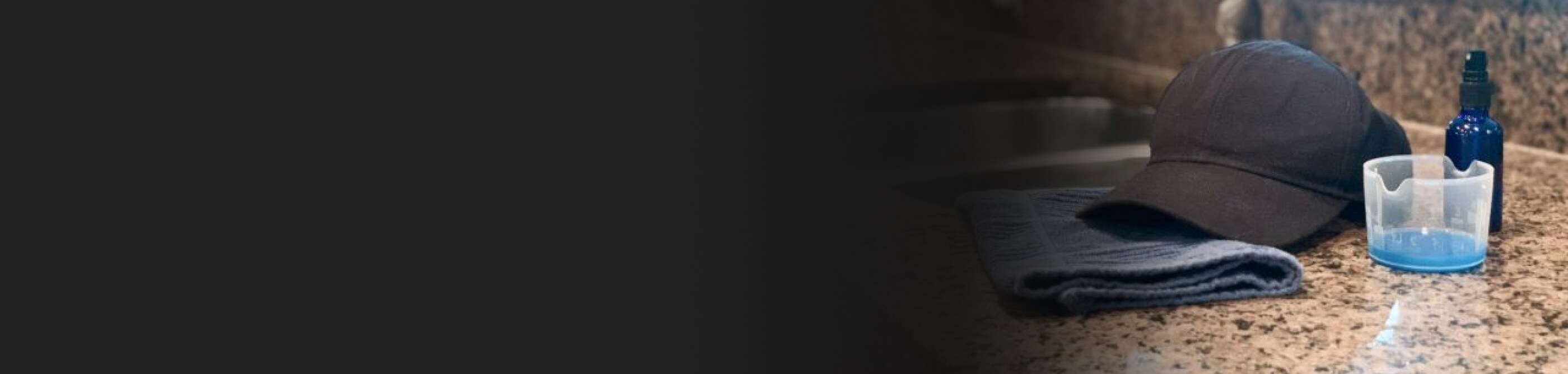 A baseball cap and cleaning supplies next to a sink