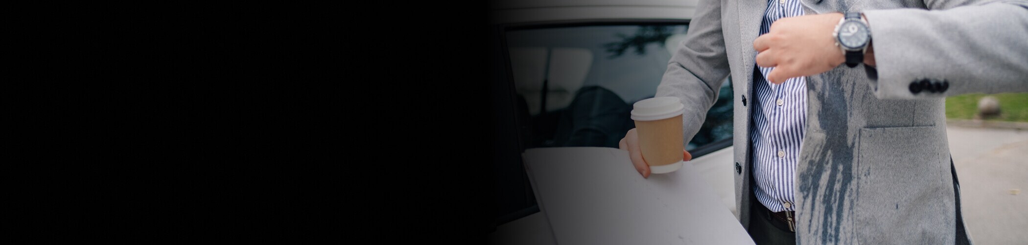 Person holding a coffee cup with a spill on their suit