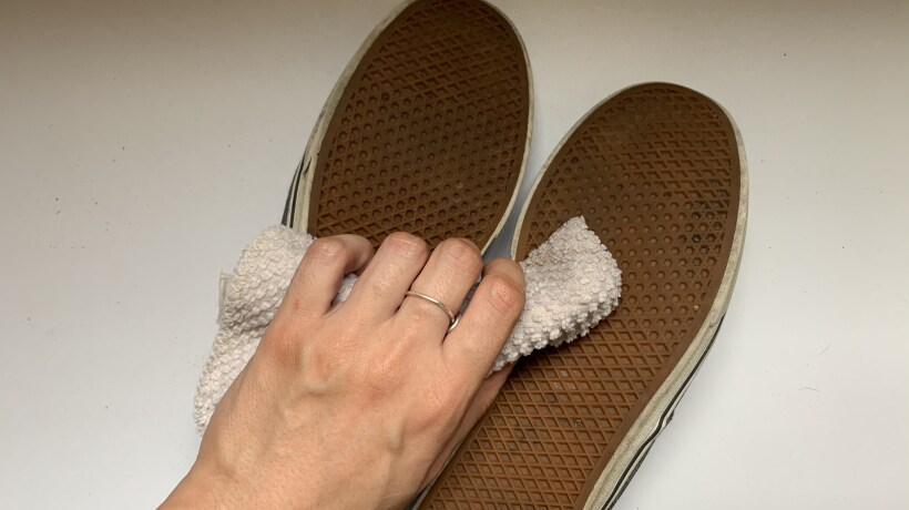 Hand wiping soles of shoes with towel