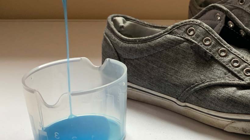 dish soap being dispensed into a small container next to shoes
