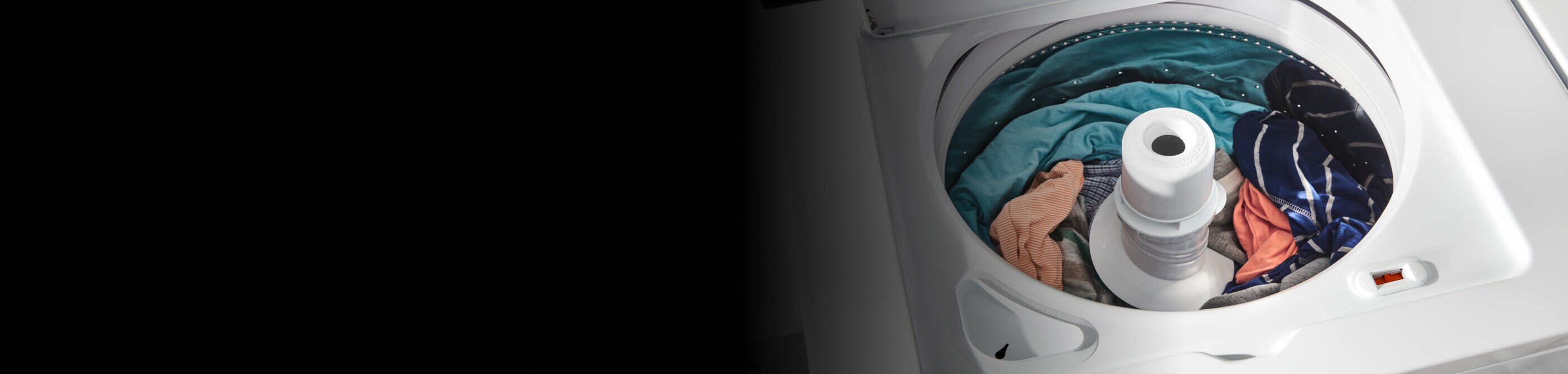 A load of orange, turquoise and blue clothes in a top load washer with an agitator