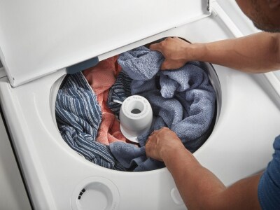 Person distributing clothes around washer agitator