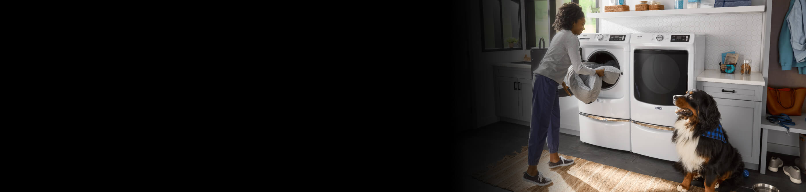 A person taking a pet bed out of a Maytag® front load washer in a laundry room