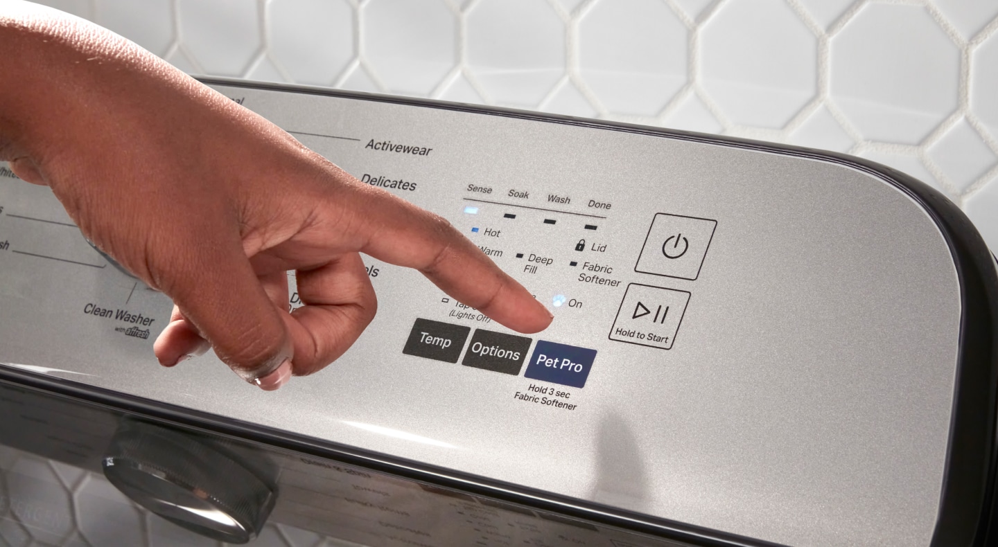 Person pressing Pet Pro button on washer Person pressing Pet Pro button on washer