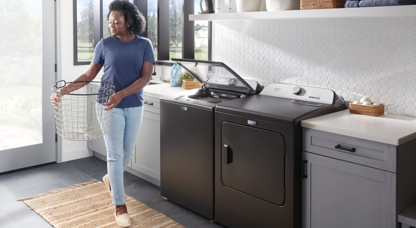 Person with laundry basket next to washer and dryer set Person with laundry basket next to washer and dryer set