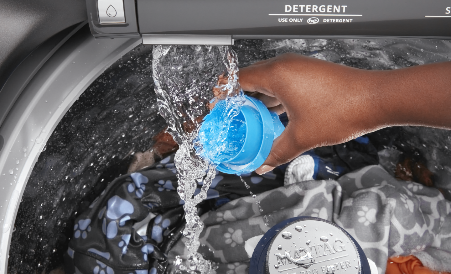 Person adding detergent to a top loading Maytag® washing machine Person adding detergent to a top loading Maytag® washing machine