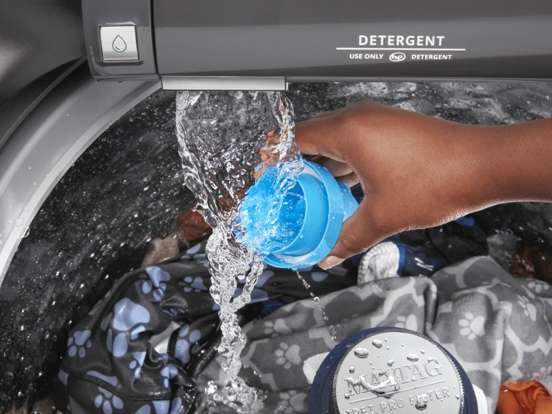 Person adding detergent to a top loading Maytag® washing machine Person adding detergent to a top loading Maytag® washing machine