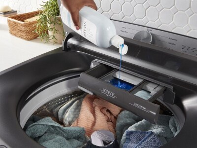 Hand adding Swash® detergent to a washer