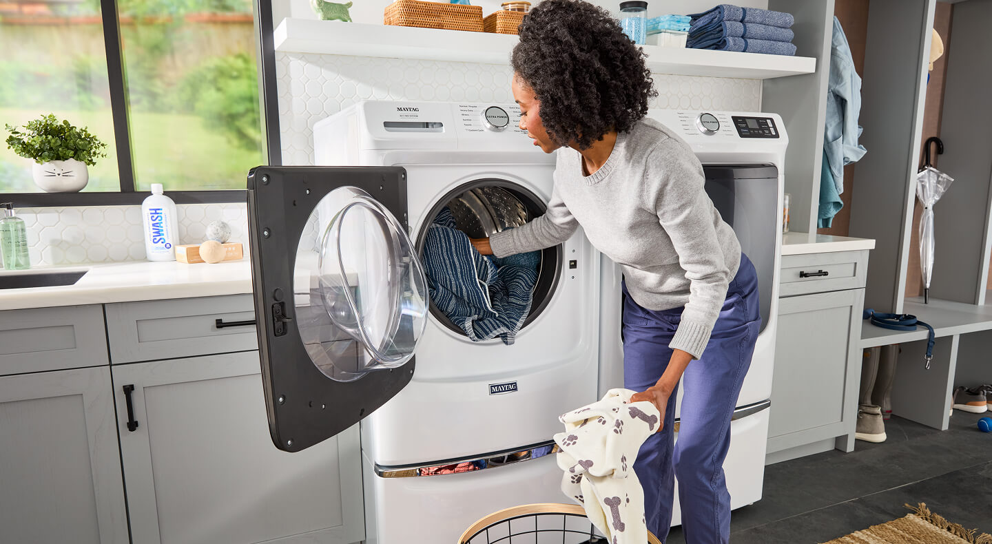 Person adding laundry to a Maytag® Front Load Pet Pro washer