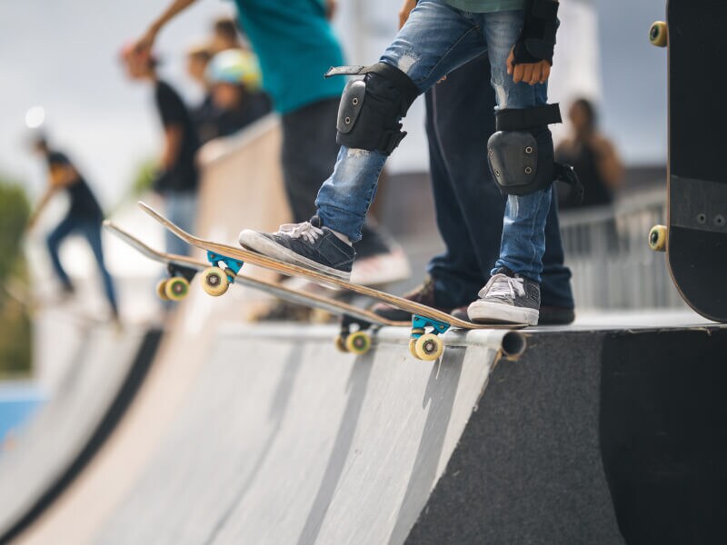 A person standing on a skateboard with knee pads on