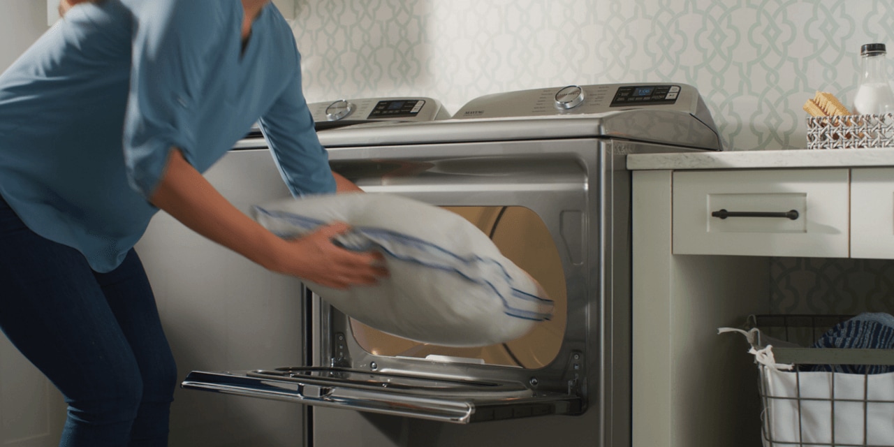 Woman loading a pillow into a Maytag® dryer Woman loading a pillow into a Maytag® dryer