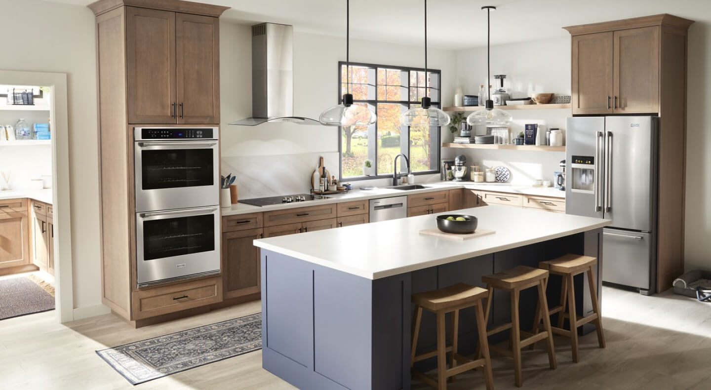 A kitchen with a double wall oven, stainless steel appliances and an island