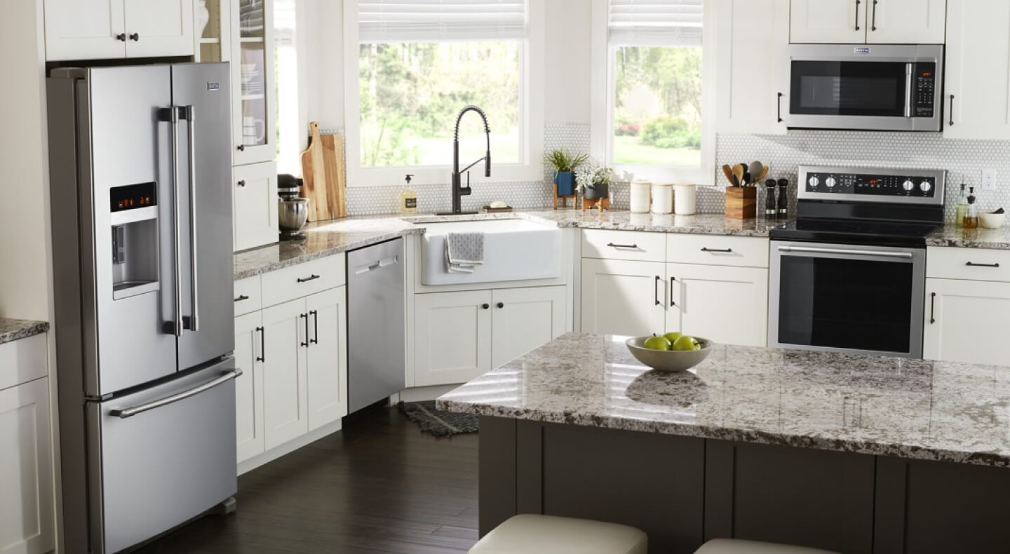 A kitchen with white cabinets, stainless steel appliances and counter seating