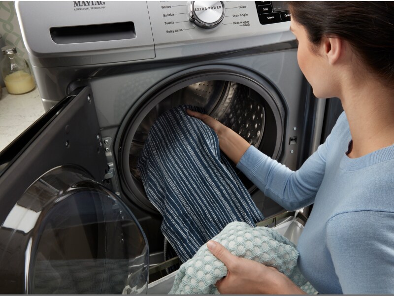Woman loading towels into a front-load washing machine Woman loading towels into a front-load washing machine