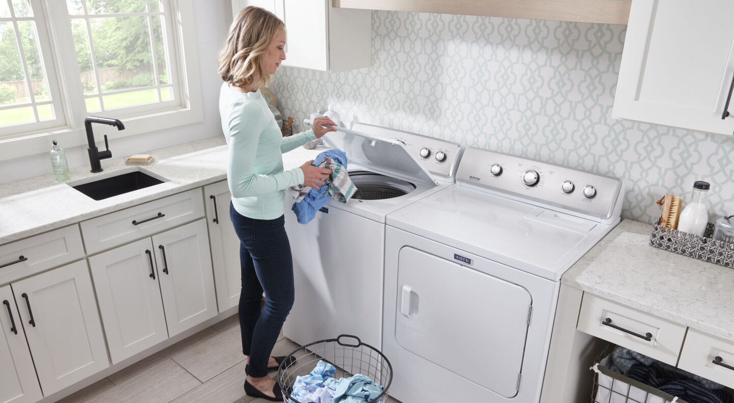 Placing clothes into a Maytag® top-load washing machine