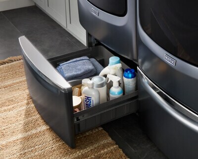 An open laundry pedestal with laundry supplies inside