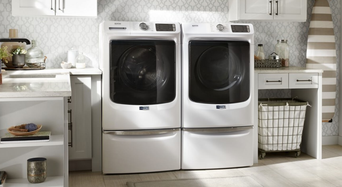 A Maytag® laundry pair in a laundry room with white cabinets