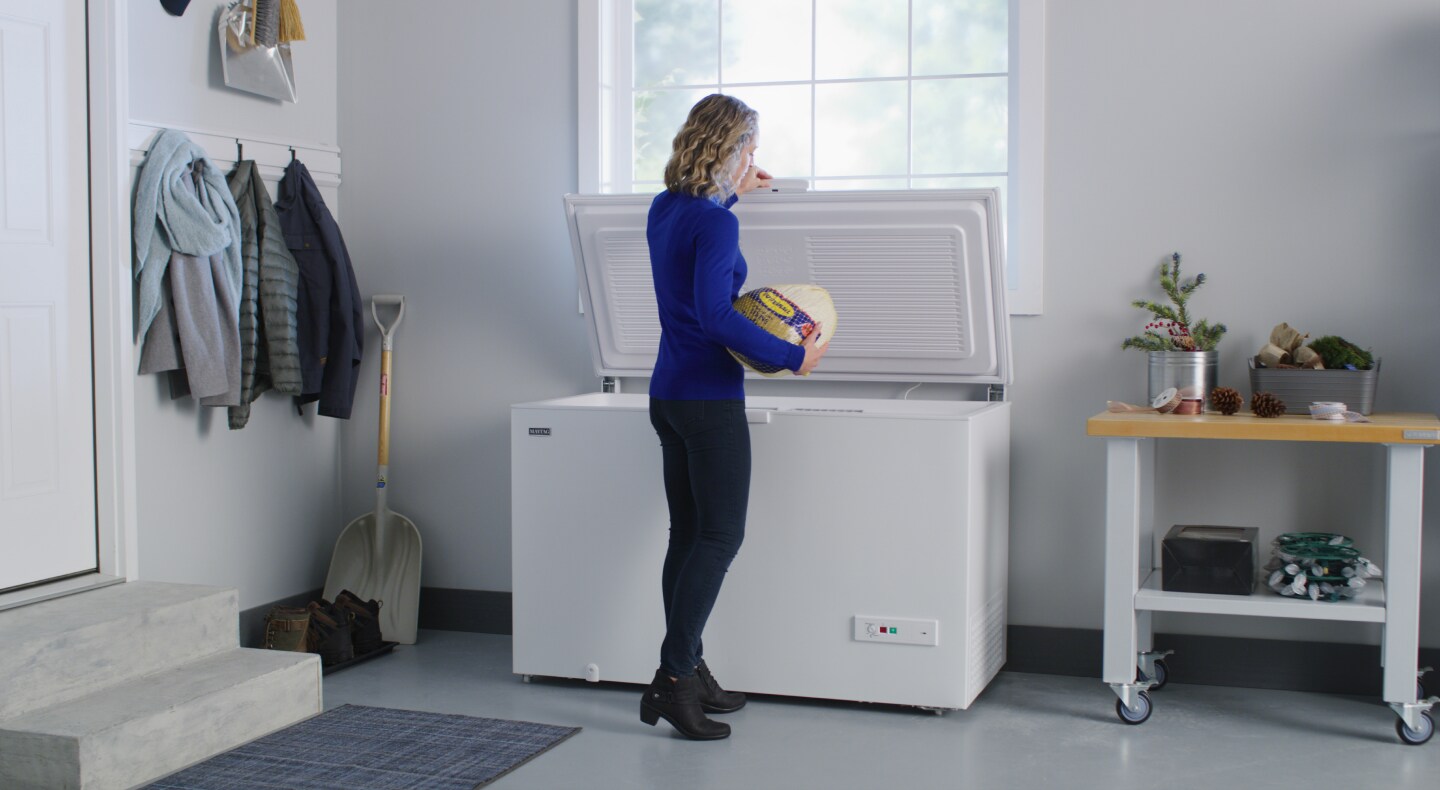 Person putting frozen turkey into a chest freezer Person putting frozen turkey into a chest freezer
