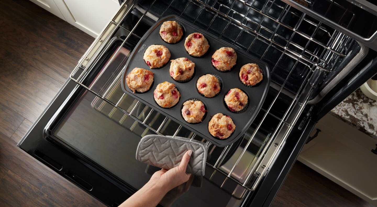 A tray of muffins being pulled from an oven