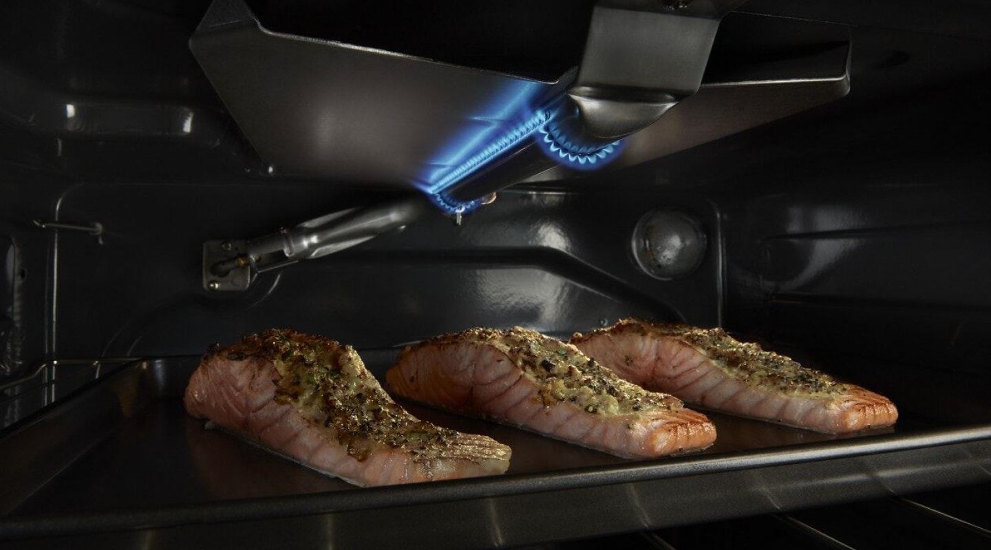 Three salmon filets broiling in an oven. Three salmon filets broiling in an oven.