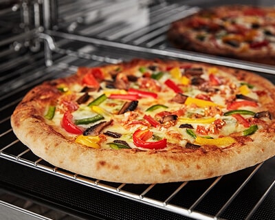 Pizza baking on a rack in a microwave cavity