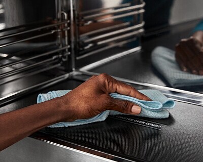 Person wiping the interior of a turntable-free microwave