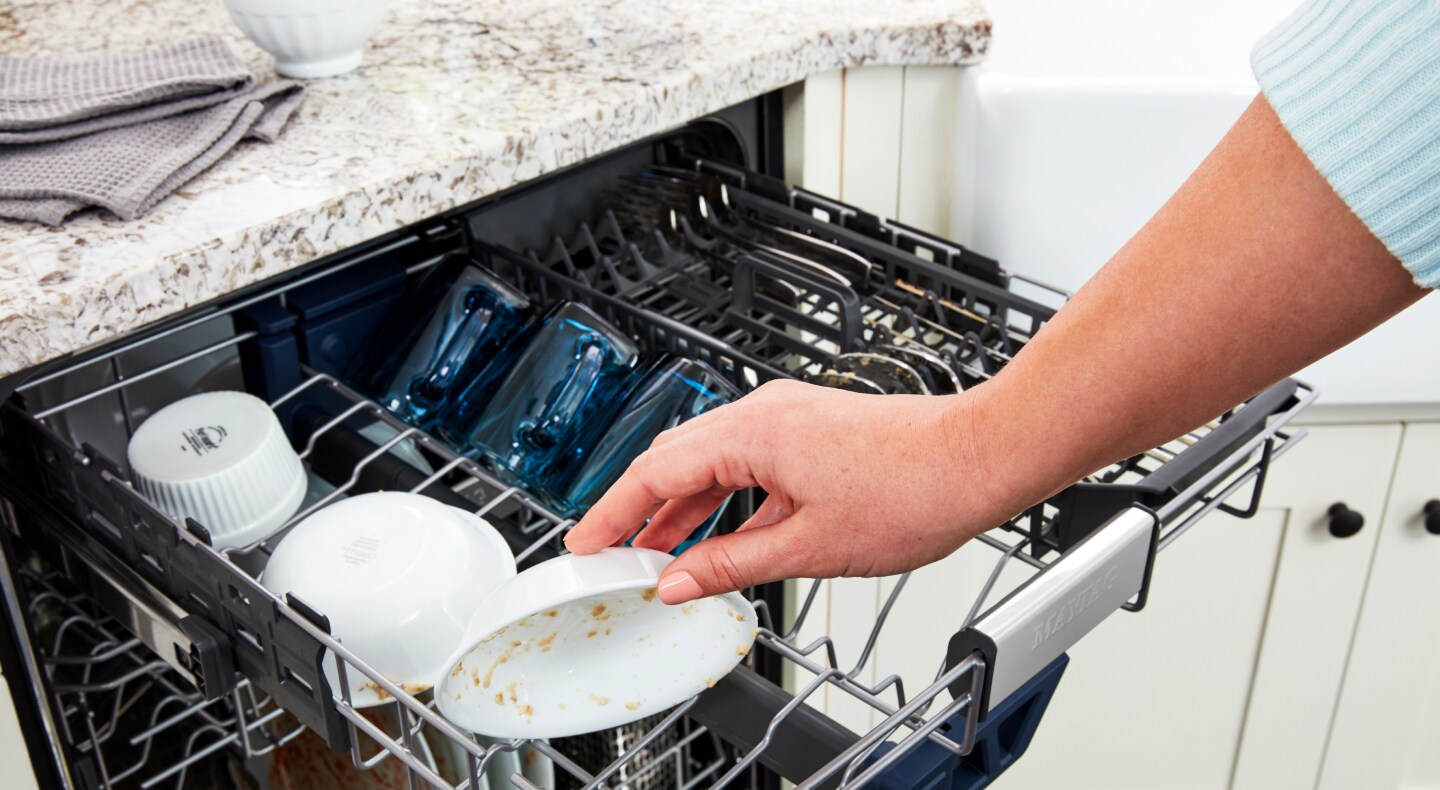 A person loading dirty dishes into a dishwasher A person loading dirty dishes into a dishwasher