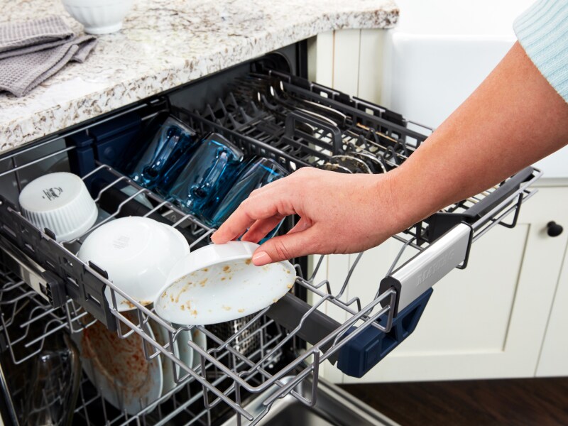 A person loading dirty dishes into a dishwasher A person loading dirty dishes into a dishwasher