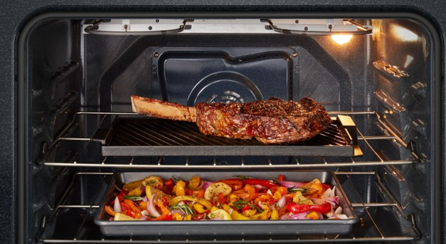 Steak and vegetables cooking inside an oven Steak and vegetables cooking inside an oven