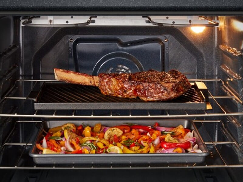 Steak and vegetables cooking inside an oven Steak and vegetables cooking inside an oven