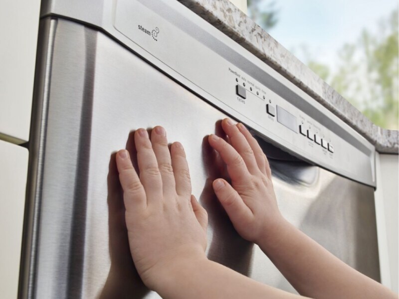 A child’s hands on a dishwasher A child’s hands on a dishwasher