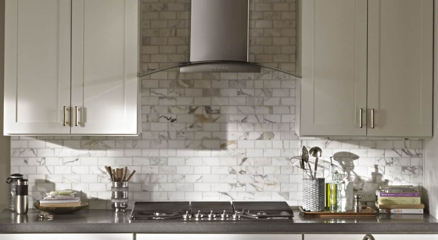 Kitchen with white backsplash and stainless steel range hood