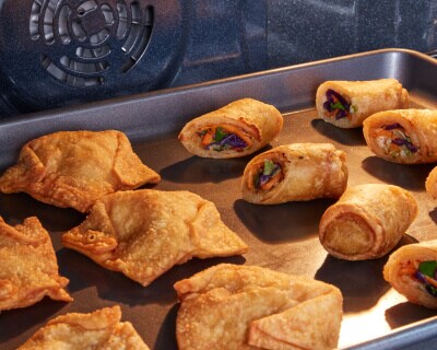 A pan of potstickers and egg rolls in an oven