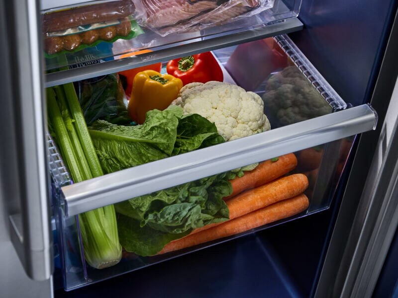 A refrigerator drawer with vegetables in it