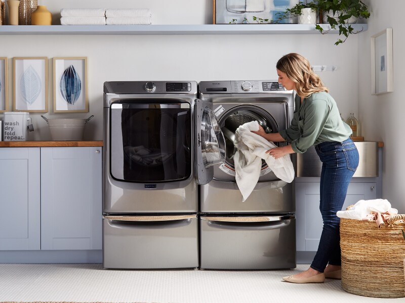 Person unloading laundry from a dryer Person unloading laundry from a dryer