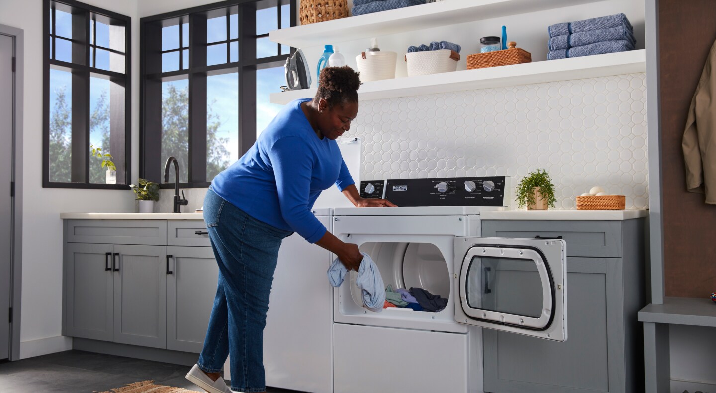 Person loading laundry into a commercial-grade dryer Person loading laundry into a commercial-grade dryer