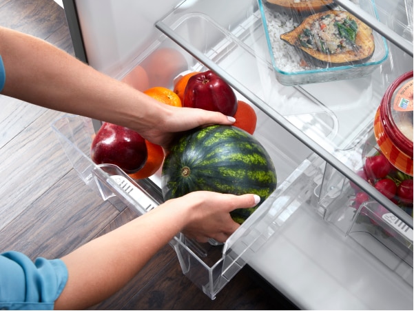 Person placing fruit in a refrigerator produce drawer