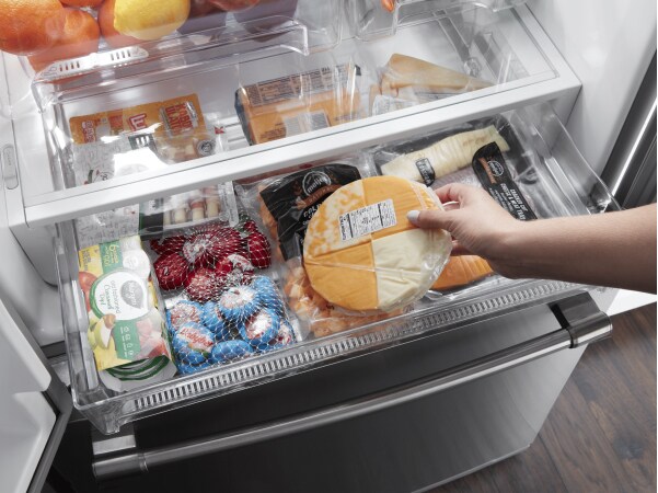 Person loading food into a refrigerator drawer
