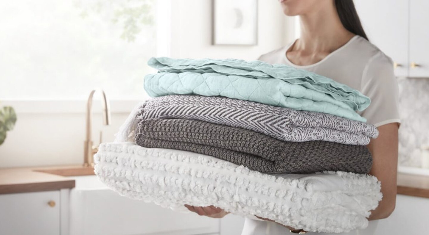 Person carrying a load of clean folded clothes