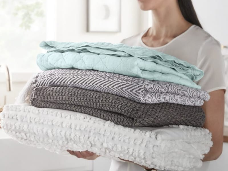 Person carrying a load of clean folded clothes