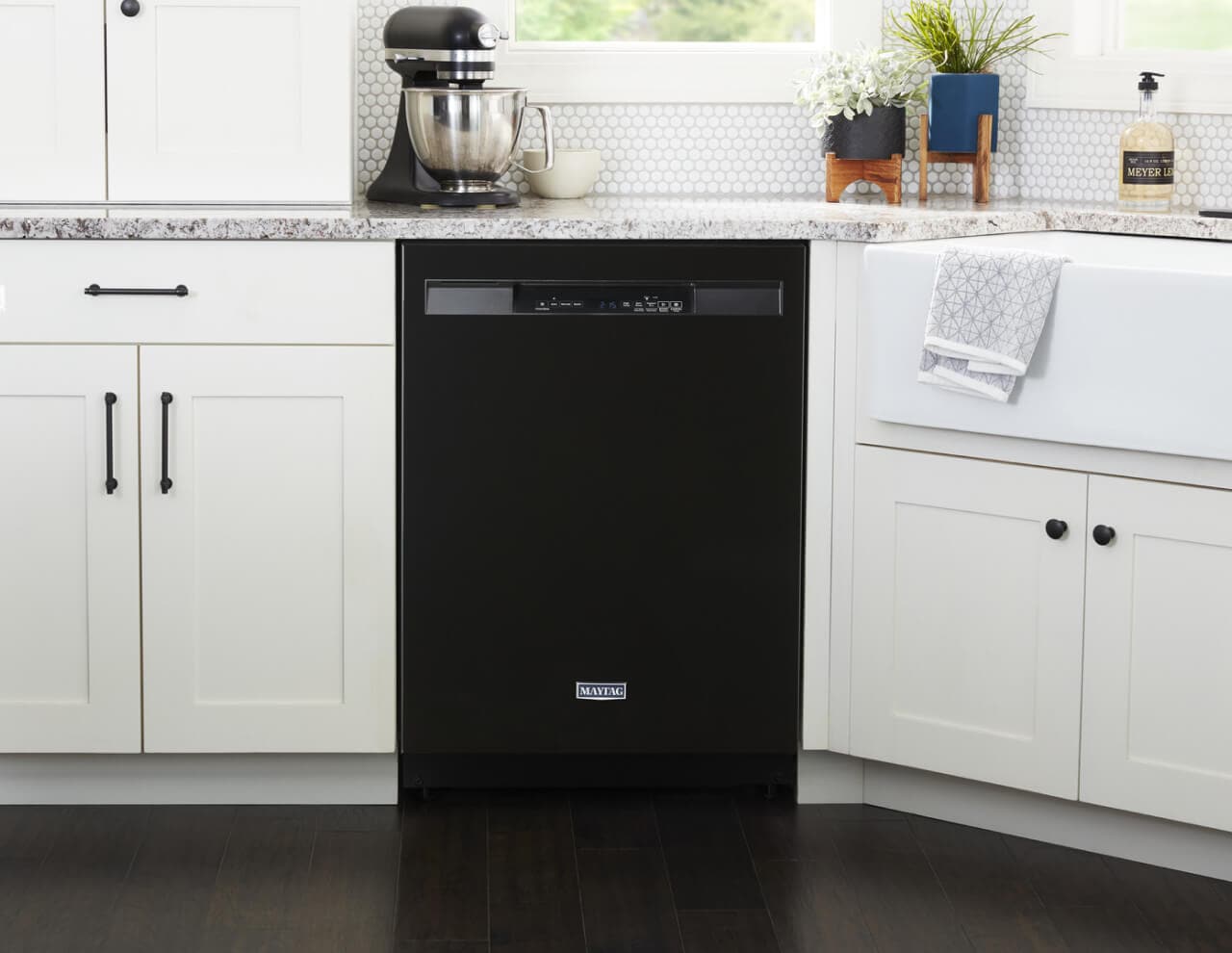 A black dishwasher set against white cabinets 
