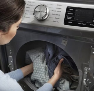 Person loading laundry into a front load dryer