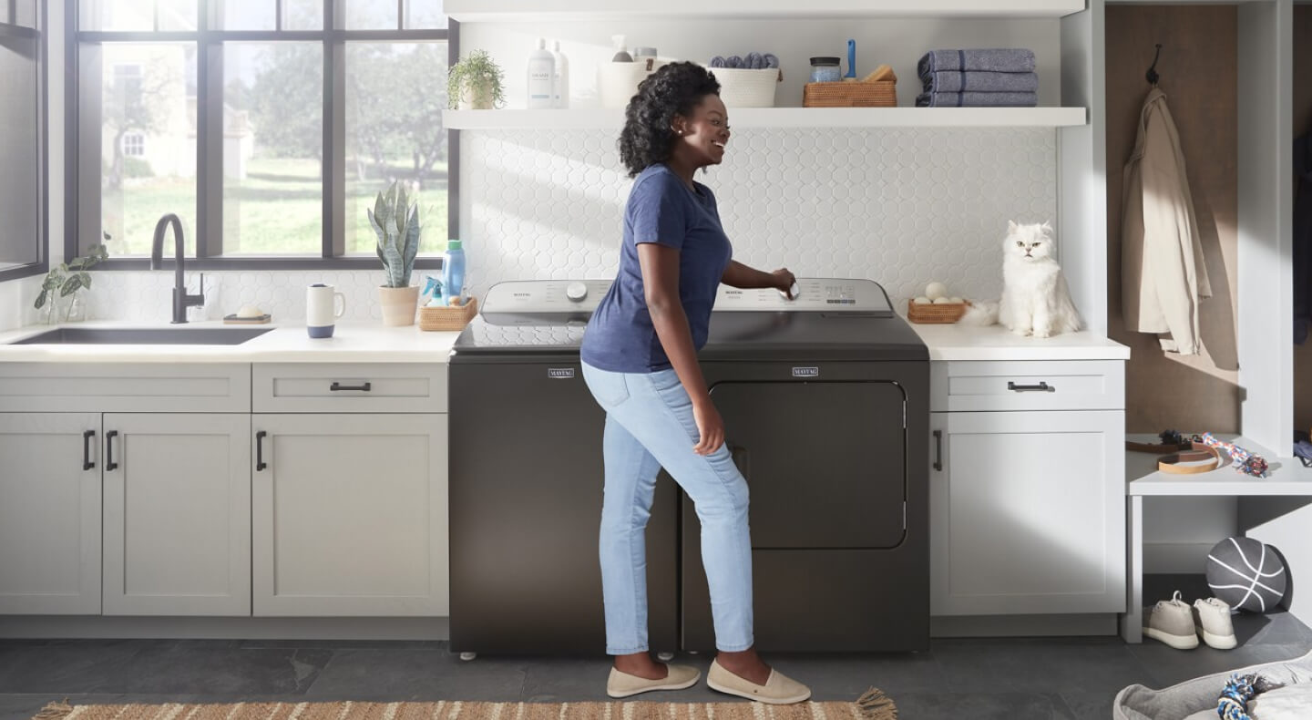 A person standing in front of a Maytag® washer and dryer set