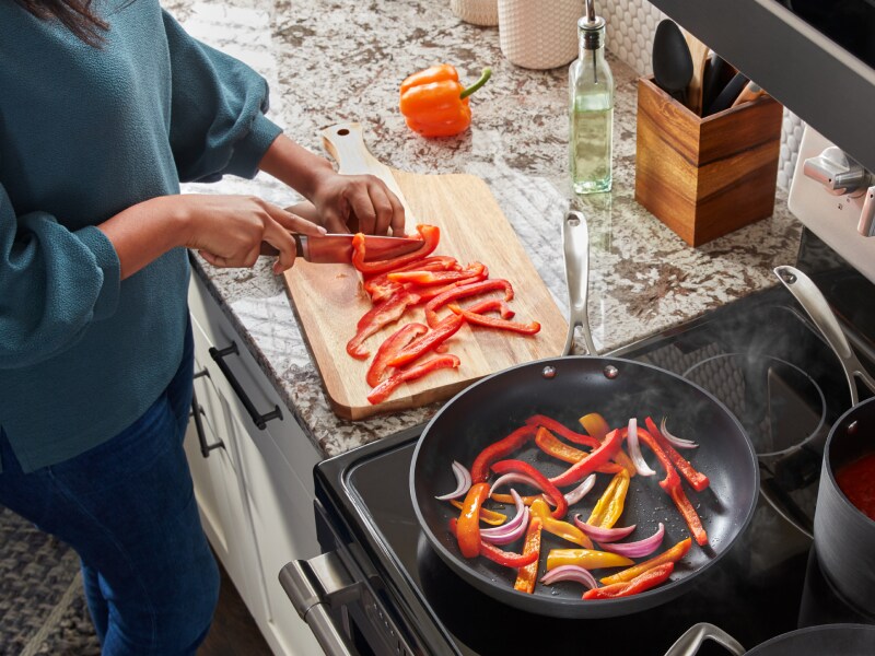 Person slicing peppers on a cutting board Person slicing peppers on a cutting board