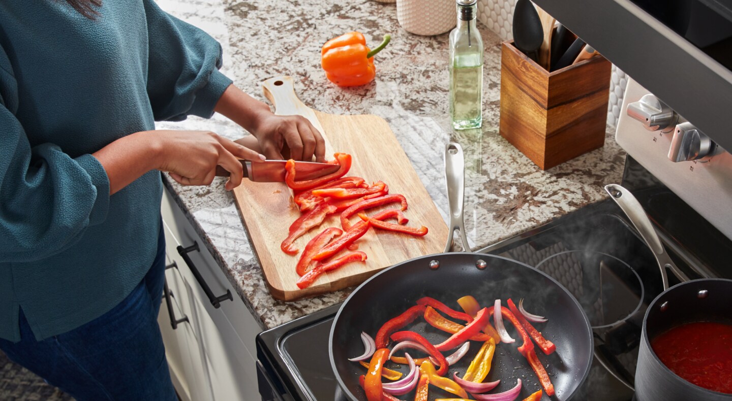 Person slicing peppers on a cutting board Person slicing peppers on a cutting board