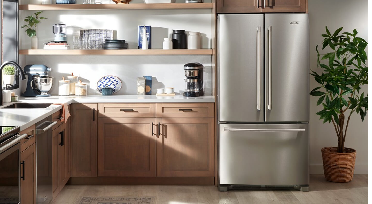 Kitchen with light brown cabinetry and stainless steel Maytag® appliances