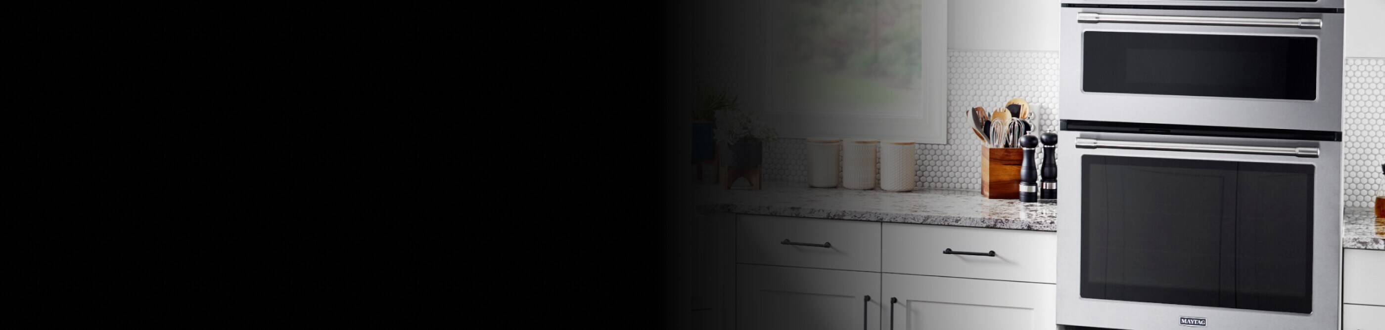 A Maytag® wall oven microwave combo placed between white cabinets with gray countertops