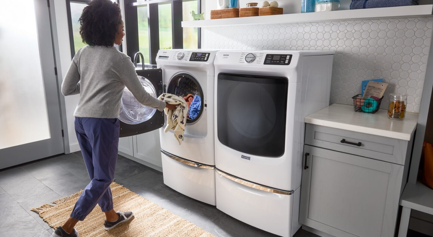 Person loading clothes into a white front load washer