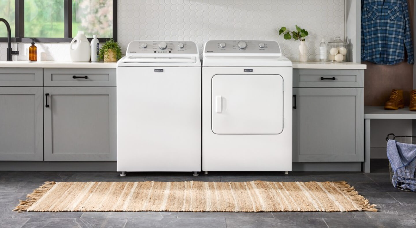 White Maytag® top load laundry pair in laundry room with gray cabinetry