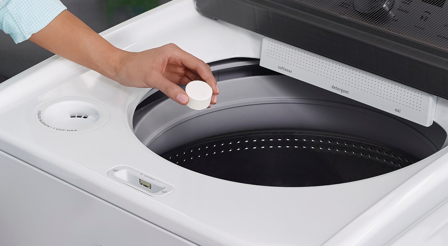 Person adding a washing machine cleaner tablet to a washing machine